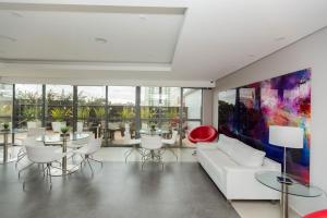 una sala de estar con un sofá blanco y mesas. en Studio Moderno no Centro com Piscina, Vista Panorâmica e Garagem, en Curitiba