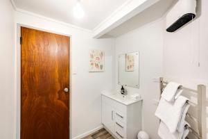 a bathroom with white walls and a wooden door at The Boat House - Ahuriri in Napier +20 photos