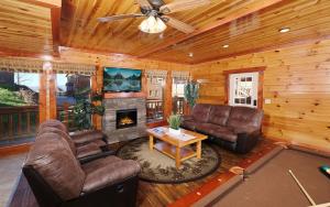a living room with leather furniture and a fireplace at Splash N Mountain Lookout in Pigeon Forge
