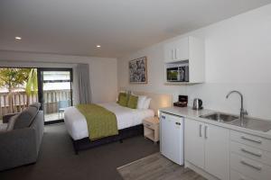 a bedroom with a bed and a kitchen with a sink at Peninsula Motel in Whitianga