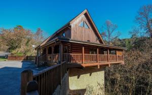 a log cabin with a wrap around deck at Bearfoot Memories - Large Game Room, Outdoor Hot Tub + Community Pool Access in Henderson Springs