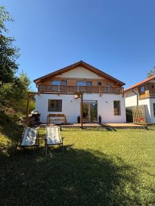 a house with two chairs in the yard at Casa Aluna Duo in Bran