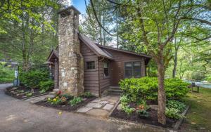 a small cabin with a stone chimney and a tree at On the River in Gatlinburg