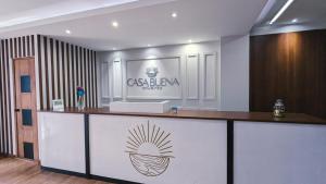 Un mostrador de recepción con un cartel en la pared. en Casa Buena Hotel, en Quetzaltenango