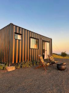 une petite maison avec quelques chaises devant dans l'établissement Hospedagem Morro do Buda Container, à Planalto