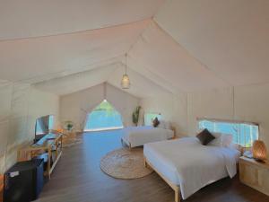 a bedroom with two beds and a tv in a tent at La Vela Legacy Resort in Thôn Dương Xuân Hạ +34 photos