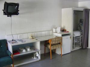 a small kitchen with a desk and a refrigerator at Central Motel in Rarotonga