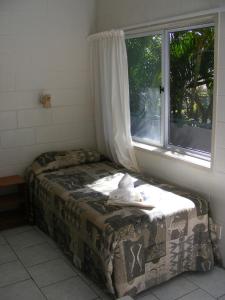 a small bed in a room with a window at Central Motel in Rarotonga