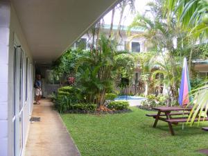 a porch of a house with a picnic table and palm trees at Central Motel in Rarotonga