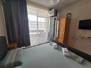 a bedroom with a bed and a large window at Студиa Блу минута от плажа in Pomorie