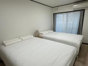 two white beds in a room with a window at West Shinjuku Nakano Family Inn in Tokyo