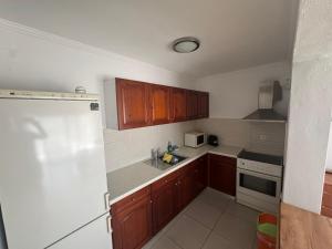 eine Küche mit Holzschränken und einem weißen Kühlschrank in der Unterkunft Τhe Sunny Apartments in Igoumenitsa + 16 Fotos
