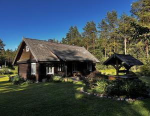 a small wooden house with a grass yard at Rustic Guesthouse in Pine Forest in Mikašiunai