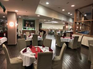a dining room with white tables and chairs and tablesearcher at Castellum Apartmanház in Gyula
