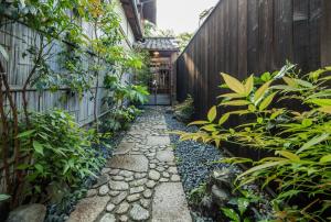 a garden with a stone walkway in front of a fence at Machiya Maya Gion in Kyoto