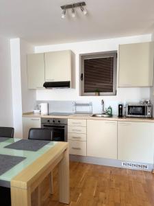 a kitchen with white cabinets and a table and a sink at Infinity Apartment Blue Horizont Przno in Budva +5 photos