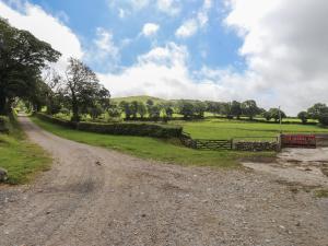 a dirt road with a fence and a field at Coetsiws in Clynnog-fawr