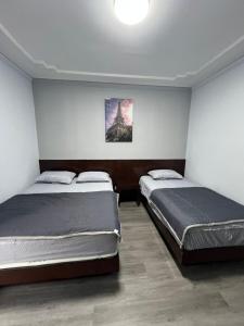 a bedroom with two beds and a painting on the wall at Eiffel Villa Homestay in Simpang Empat