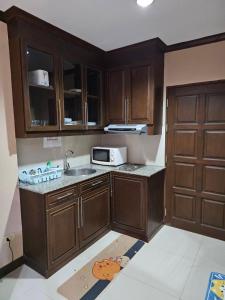 a kitchen with wooden cabinets and a sink and a microwave at วิวทะเล5 c in Ban Chek