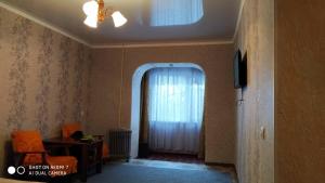 una sala de estar con una ventana con una cortina blanca en Квартира абдрахманова, en Karakol