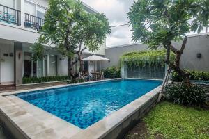 a swimming pool in front of a house with trees at Mi Casa Residence in Seminyak