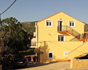 una casa gialla con una macchina parcheggiata di fronte di Bacan Serviced Apartments a Cavtat