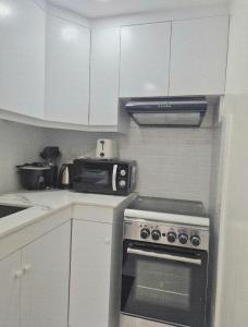 eine Küche mit Herd und Mikrowelle in der Unterkunft Modern Minimalist 1BR Condotel at BGC Taguig in Taguig