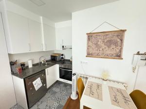 una pequeña cocina con armarios blancos y una mesa en Falperra Estudio, en Vigo 18 fotos más