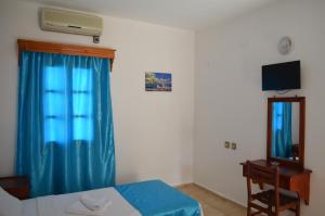 グムベットにあるAli Baba Hotel Gümbetのベッドルーム1室(ベッド1台付)、青いカーテン付きの窓が備わります。