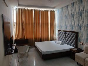 齐拉克普尔Hotel Golden Rooftop的一间带床和椅子的小卧室