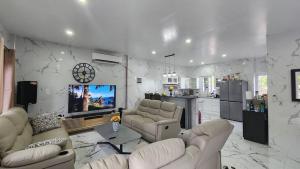 a living room with couches and a tv and a kitchen at Stargazers Luxury Condo Complex apartments in Ocoy