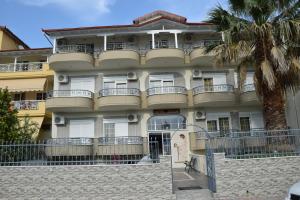 a large building with a palm tree in front of it at Hotel Jason in Paralia Katerinis