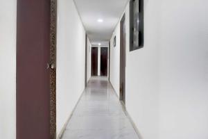 a hallway with white walls and a white tile floor at Hotel O Talwade in Pune