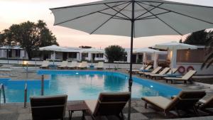 a large swimming pool with chairs and an umbrella at Hotel Melikari in Skiros