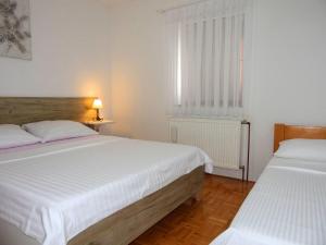 two beds in a white room with a window and a bed sidx sidx at Apartment Golden Fields in Smoljanac