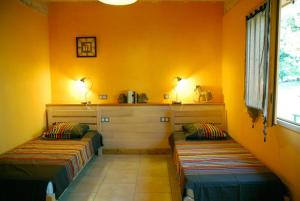 - 2 lits dans une chambre aux murs orange dans l'établissement Gîte des Conquettes, à Salles-la-Source