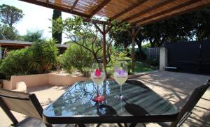 a glass table with two wine glasses on a patio at Chez Chris in Fréjus