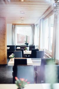 una sala de conferencias con mesas, sillas y ventanas en Hotel Filli, en Scuol