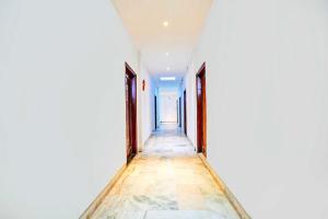 un corridoio vuoto con pareti bianche e pavimento piastrellato di Hotel O Gurudwara Square a Gwalior