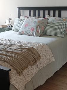 a bed with a blanket and pillows on it at Casa da Beira Rio in Marco de Canaveses