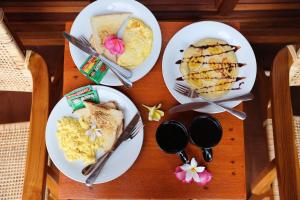 3 Teller mit Frühstücksspeisen auf einem Holztisch in der Unterkunft Belangga Cottage in Nusa Penida