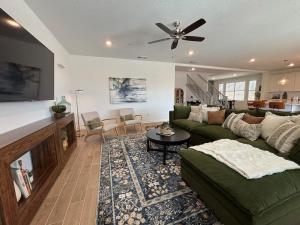 a living room with a green couch and a ceiling fan at Joyhouse in Visalia