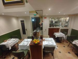 a restaurant with tables and chairs and a person standing in the mirror at Hotel Modern Est in Paris
