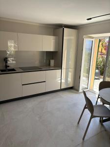 Una cocina con gabinetes blancos y una mesa y sillas. en Blue Residence - Spettacolare casa a Pieve Ligure, en Pieve Ligure