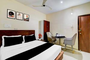 een slaapkamer met een bed, een tafel en stoelen bij Hotel O Nampally Metro Station Hyderabad in Hyderabad