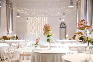 a banquet hall with white tables and chairs and lights at UKI Puhkeküla in Ranna