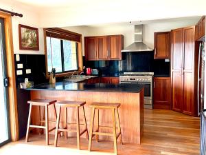 a kitchen with wooden cabinets and a island with bar stools at Bayview Heights in Kingscote