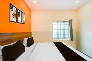 a bedroom with a bed with an orange wall at Hotel O Dilsukhnagar Metro Station in Hyderabad