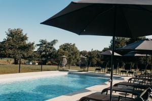 a swimming pool with chairs and umbrellas next to at Hôtel Le Chatellier - Piscine chauffée d'avril à octobre in Cancale