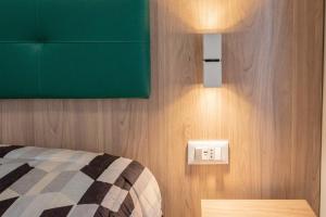 a bedroom with a bed with a green headboard and a light switch at Il Risveglio del Cavaliere Casa Vacanza in Gioia dei Marsi